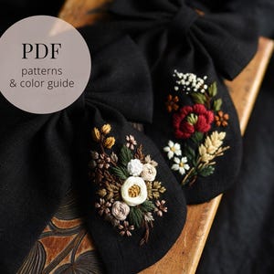 Op de afbeelding: Twee zwarte stoffen strikken met geborduurde bloemmotieven. Eén strik heeft een boeket van witte, gele en bruine bloemen. De andere strik heeft een rode bloem met witte en gele accenten. De tekst "PDF patterns & color guide" staat in een cirkel.