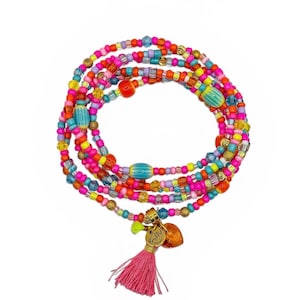 Könnte beinhalten: Ein farbenfrohes Perlenarmband mit einem rosa Quastenanhänger und goldenen Charms. Das Armband besteht aus Perlen in Pink, Orange, Gelb, Blau und Grün. Die Charms umfassen ein Herz und ein kleines Etikett.
