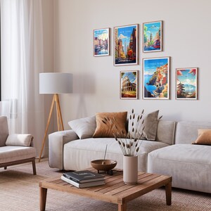 May include: A living room interior with a white couch and a wooden coffee table. The wall is decorated with six framed travel posters featuring various cities, including New York, London, Rome, and Cinque Terre.