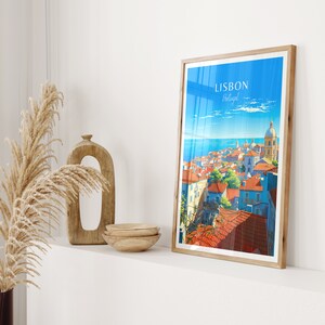 May include: A vintage travel poster with a colorful illustration of Lisbon, Portugal. The poster features a cityscape with red-tiled roofs, a blue ocean, and a white church with a dome. The text "LISBON Portugal" is printed in white on a blue background.