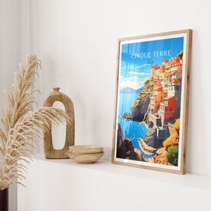 May include: A framed poster with a colorful illustration of the Cinque Terre region of Italy. The poster features a seaside town with colorful buildings built into the cliffs. The text on the poster reads "Cinque Terre, Italy".
