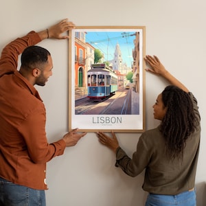Op de afbeelding: Een vintage poster met een blauwe en witte tram die door een straat in Lissabon, Portugal, rijdt. De poster heeft een bruine lijst en de tekst "LISBON, PORTUGAL" onderaan.
