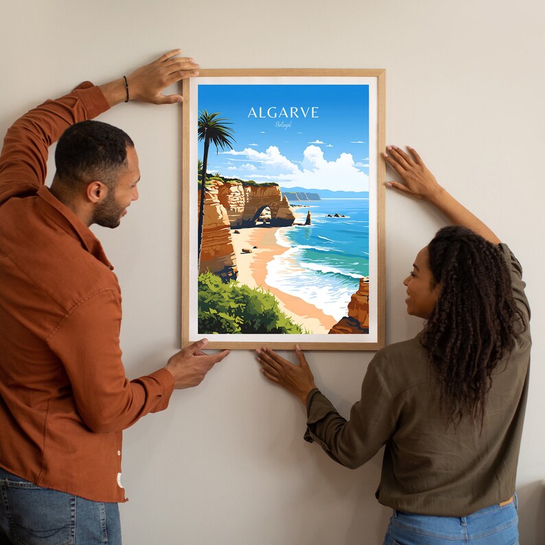 Puede incluir: Un p&oacute;ster enmarcado con una ilustraci&oacute;n colorida de una escena de playa en Algarve, Portugal. El p&oacute;ster presenta un acantilado rocoso con un arco, una playa de arena y olas azules del oc&eacute;ano. El texto "ALGARVE Portugal" est&aacute; impreso en la parte superior del p&oacute;ster.