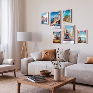 Op de afbeelding: Een woonkamer met een witte bank en een houten salontafel. Aan de muur hangen zes ingelijste reisposters, met steden zoals Santorini, Lissabon en Rome. De posters zijn in vintage stijl met kleurrijke illustraties.