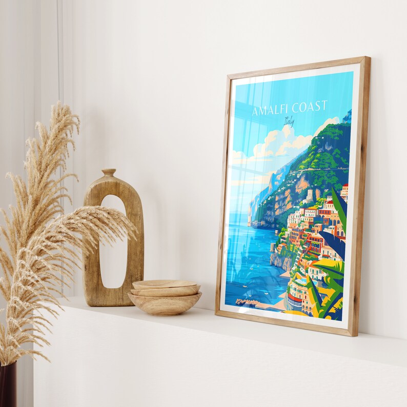 May include: A framed poster with a colorful illustration of the Amalfi Coast in Italy. The poster has the text "Amalfi Coast Italy" at the top.