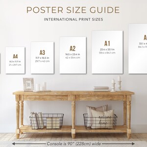 May include: A poster size guide with different sizes of paper, including A0, A1, A2, A3, A4, and A5. The sizes are listed in inches and centimeters. The poster is hanging on a white wall above a wooden console table.