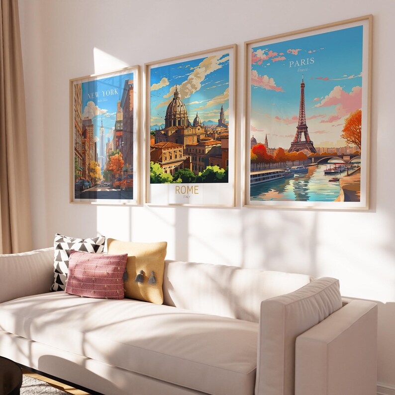 May include: Three framed travel posters featuring cityscapes. The posters are hung on a white wall above a white sofa. The posters depict the cities of New York, Rome, and Paris. The posters are in a vintage style with colourful illustrations.