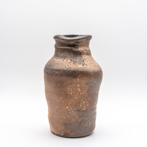 May include: A handcrafted ceramic vase with a rustic, textured appearance. The vase features a dark brown rim that fades into a lighter, speckled brown body. The unique shape and color variations suggest a natural, earthy aesthetic.
