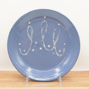 May include: A blue ceramic plate with a white design of three abstract shapes and white dots.