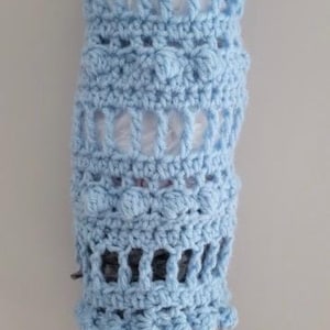 May include: A light blue crochet plastic bag holder featuring a textured pattern of bobble stitches and open vertical gaps. The text CROCHET PLASTIC BAG HOLDER BEGINNER FRIENDLY PATTERN DIGITAL PDF INSTANT DOWNLOAD is displayed at the top.