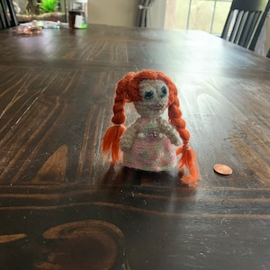 crochet mini doll with a pink dress and red braids