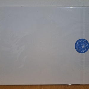 Op de afbeelding: Een blanco witte kaart met een blauwe ronde stempel waarop "Heidi South Photography" in wit staat.