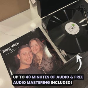 May include: A black record player with a vinyl record and a photo album. The album features a couple and the text "May 14th" with a heart. The record has a sticker that says "Made with Love". The text "UP TO 40 MINUTES OF AUDIO & FREE AUDIO MASTERING INCLUDED!" is also visible.