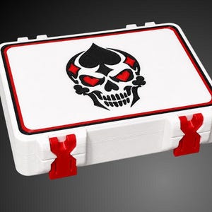 May include: A rectangular white storage case featuring a black and red graphic of a skull integrated with playing card suit symbols. The lid has a red and black border, and the case is secured by two bright red latches on the front edge.