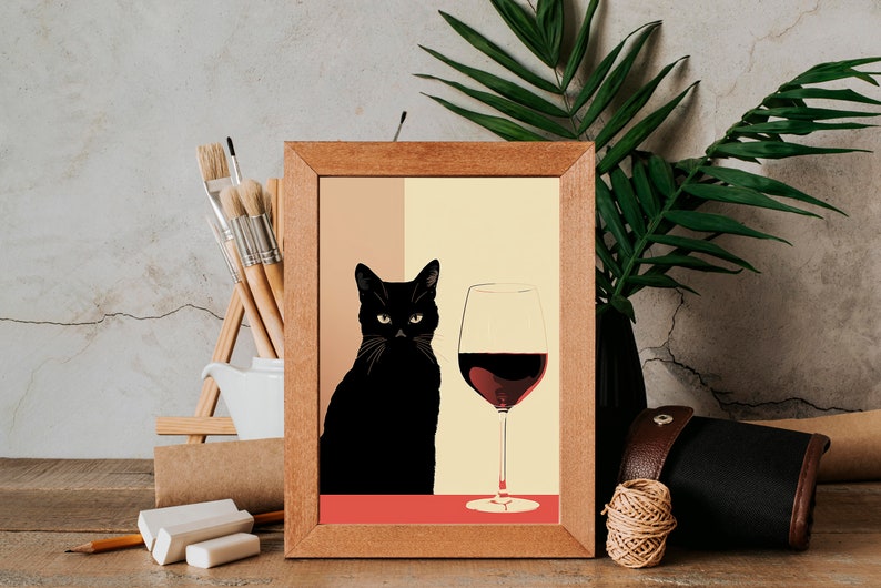 Op de afbeelding: Een ingelijst afdruk van een zwarte kat die naast een glas rode wijn zit. De achtergrond is licht beige en geel.