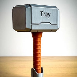 This 3D printed Thor hammer baby rattle features personalized engraving and colorful handle options like black, pink, light blue, brown, and yellow. A perfect custom baby gift and personalized baby rattle for Marvel fans.