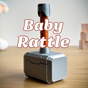 3D printed Thor hammer baby rattle with custom name engraving and multiple handle colors including black, brown, light blue, pink, and yellow. This personalized baby rattle is a unique custom baby gift perfect for little superheroes and Marvel fans.