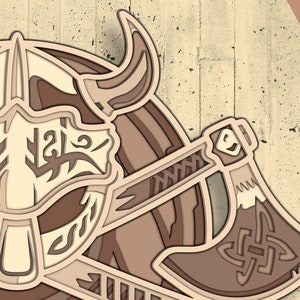 Peut inclure: Un design en papier d&eacute;coup&eacute; brun et beige d'un casque viking et d'une hache. Le casque est orn&eacute; de d&eacute;tails complexes et la hache pr&eacute;sente un motif de n&oelig;ud celtique.