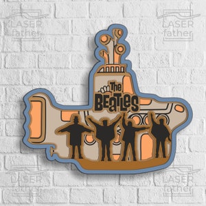 May include: A blue, yellow and brown cutout of the Beatles' Yellow Submarine with the band members standing on the deck. The text "The Beatles" is written on the front of the submarine.