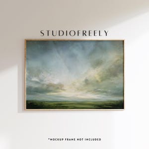 May include: An abstract landscape painting in a wooden frame. The artwork depicts a cloudy sky with shades of blue, gray, and yellow over a green field. The text "STUDIOFREELY" is at the top. The text "*MOCKUP FRAME NOT INCLUDED" is at the bottom.