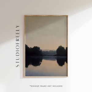 May include: A framed landscape art print featuring a serene lake scene at dusk. The artwork depicts a calm body of water reflecting the silhouettes of trees and a soft, muted sky. The frame is a light wood color, and the print has a calming, neutral color palette.