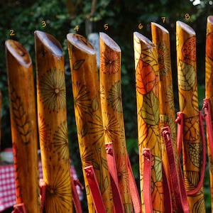 Bastones artesanales de madera decorados con pirograbado y pintura.