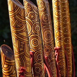 Bastones artesanales de madera decorados con pirograbado y pintura.