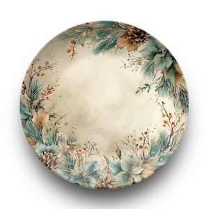Può includere: Piatto decorativo rotondo con un design ad acquerello. Il piatto presenta un centro color crema circondato da un bordo di aghi di pino, pigne e bacche nei toni del verde, marrone e arancione. Il piatto ha uno sfondo bianco.
