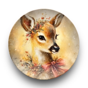 May include: A round decorative plate with a watercolour painting of a fawn. The fawn has brown fur, large dark eyes, and is adorned with a floral crown and a pink bow. The background is a soft, warm yellow.