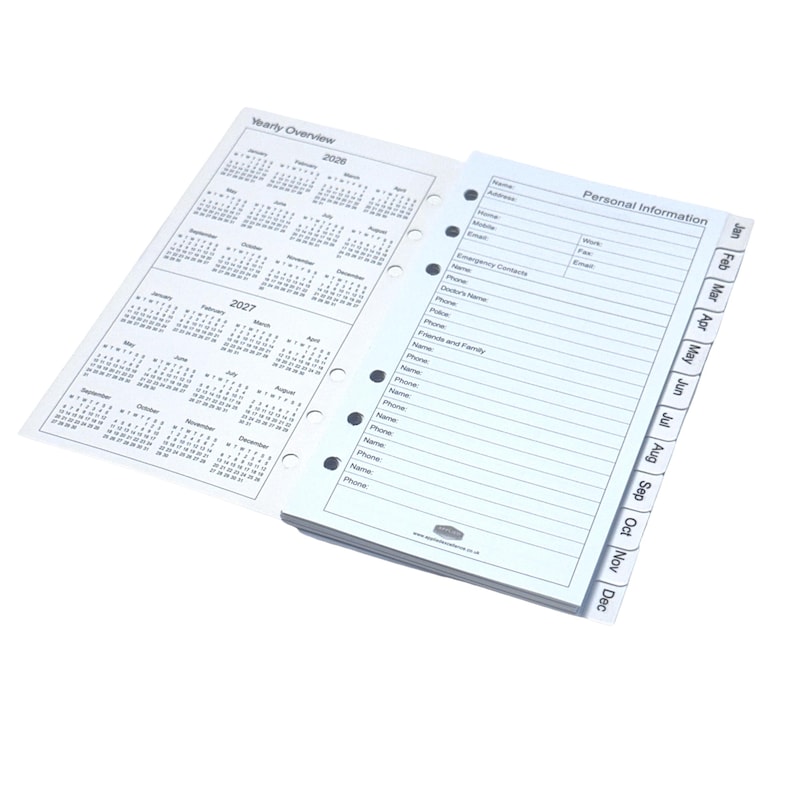 May include: An open white planner with a yearly overview calendar for 2026 and 2027. The right side features personal information pages with monthly tabs from Jan to Dec. The planner is designed for organization and note-taking.