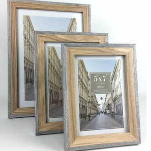 May include: Three wooden photo frames with a distressed grey and brown finish. The frames are arranged in a staggered display, each holding a photograph. The visible text on the frame reads "5x7" (13 x 18cm).