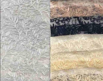 Puede incluir: Una variedad de telas de encaje en diferentes colores. El lado izquierdo presenta un encaje floral blanco, mientras que el lado derecho muestra muestras en gris, rosa, azul marino, crema y otros tonos. El encaje tiene un diseño delicado y detallado.