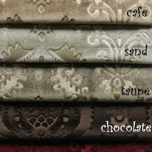 Op de afbeelding: Een close-up van stofstalen in verschillende kleuren en patronen, waaronder wit, ivoor, cafe, zand, taupe, chocolade, bordeauxrood, goud en marine. De stof heeft een damastpatroon.