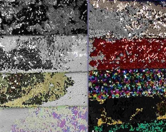 May include: A close-up of a variety of iridescent sequin fabrics in different colors, including black, silver, gold, red, green, blue, and rainbow. The sequins are arranged in horizontal stripes.