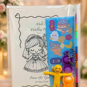 May include: A clear plastic bag containing a wedding favor set. The set includes a card with a bride and groom illustration, stickers, a rainbow pen, a keychain, a yellow figure, and a purple and orange toy. The card reads "Milo's Wedding Party".