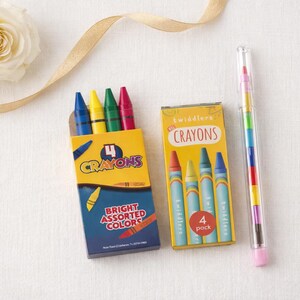 May include: Two boxes of crayons, one with four crayons and the other with a crayon stick. The boxes are yellow and blue, with the words "Crayons" and "Bright Assorted Colors" printed on them. A single crayon stick is in a clear tube.