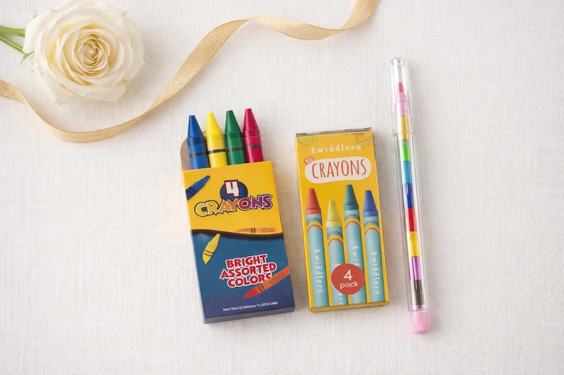 May include: Two boxes of crayons, one with four crayons and the other with a crayon stick. The boxes are yellow and blue, with the words "Crayons" and "Bright Assorted Colors" printed on them. A single crayon stick is in a clear tube.