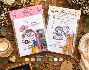 May include: Two wedding activity packs in clear plastic sleeves with personalized headers. One features a car illustration with balloons, the other a bride and groom. Each includes a small toy, a bubble wand, and a pack of four wax crayons.