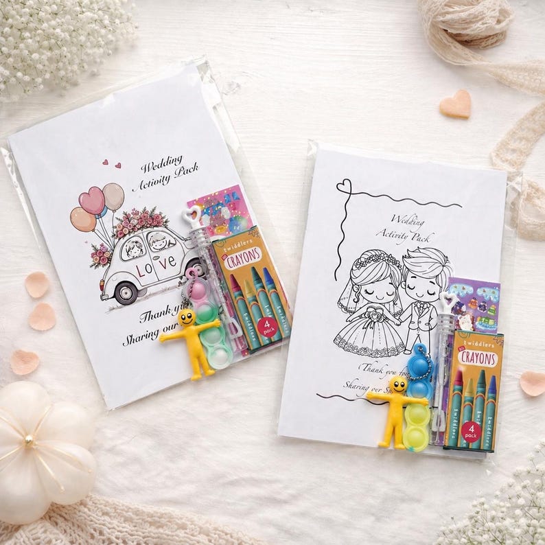 May include: Two white Wedding Activity Packs with illustrations. One pack features a car with flowers and balloons, the word "Love", and a crayon pack. The other pack has a bride and groom illustration and a crayon pack.