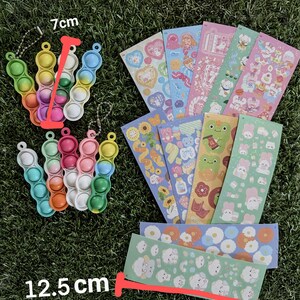 May include: A collection of colorful sensory toys and sticker sheets. The sensory toys are 7 cm long and 12.5 cm wide, featuring a bubble-popping design in various colors. The sticker sheets showcase cute illustrations.
