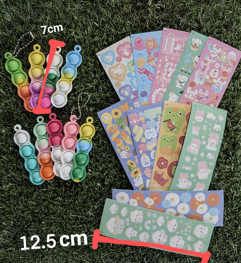 May include: A collection of colorful sensory toys and sticker sheets. The sensory toys are 7 cm long and 12.5 cm wide, featuring a bubble-popping design in various colors. The sticker sheets showcase cute illustrations.