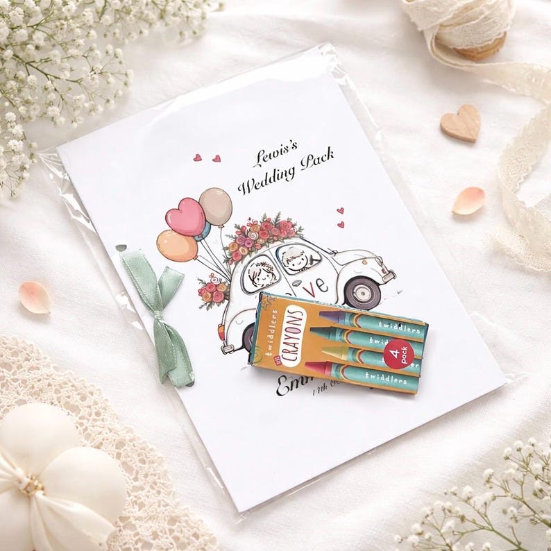 May include: A wedding pack with a cartoon illustration of a car carrying a bride and groom, balloons, and flowers. The pack includes a small box of crayons. The text on the pack reads "Lewis's Wedding Pack".