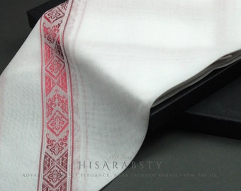 May include: White cotton fabric with a red and white embroidered border. The fabric is folded and draped over a black box. The text "HISARABSTY" is visible on the fabric.