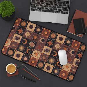 Puede incluir: Una alfombrilla de ratón marrón y negra con un patrón repetitivo de soles, lunas y estrellas. El patrón es de estilo patchwork, con cada cuadrado con un diseño diferente.