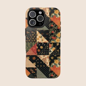 以下が含まれることがあります： パッチワークのデザインの携帯電話ケース。ケースは、黒、オレンジ、黄色、緑の色合いのさまざまな花柄と幾何学模様が特徴です。ケースは光沢仕上げで、カメラの切り抜きがあります。