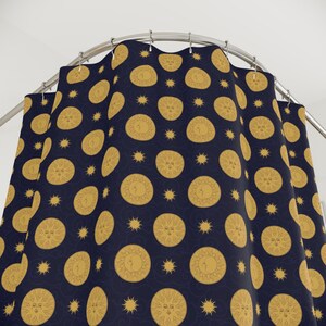 May include: A navy blue shower curtain featuring a repeating pattern of gold sun and moon faces, and star shapes. The celestial design is set against a dark background, creating a whimsical bathroom accessory.