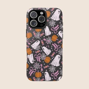 May include: A black phone case with a repeating pattern of white ghosts, orange pumpkins, pink bows, spiderwebs, and candy. The case has a glossy finish and a camera cutout.