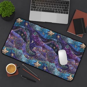 May include: A blue and purple galaxy-themed mousepad with gold accents and stars. The mousepad has a quilted texture and a black border.