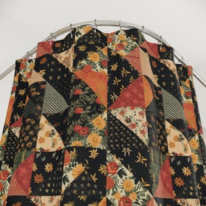 May include: A patchwork shower curtain with a floral design. The curtain features a mix of triangles in black, red, orange, and beige, adorned with flowers and star-shaped accents. The curtain hangs from a curved metal rod.