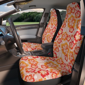 May include: Car seat covers with a bright floral design in orange, red, and yellow on a pale beige backdrop. The hibiscus flower pattern gives a tropical feel to the car's interior. The covers are visible on the driver and passenger seats.